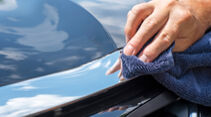 Close-up man polishing chrome trim on new black car