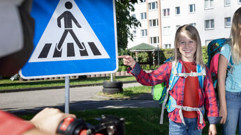Smiling boy pointing at pedestrian sign