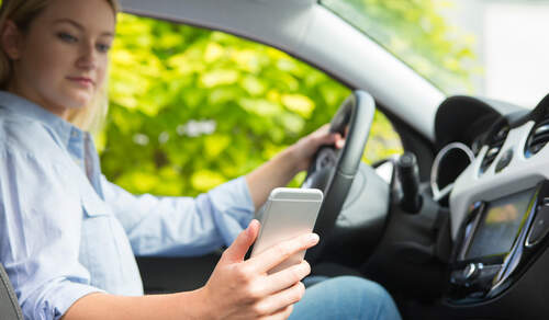 Woman In Car Texting On Mobile Phone Whilst Driving