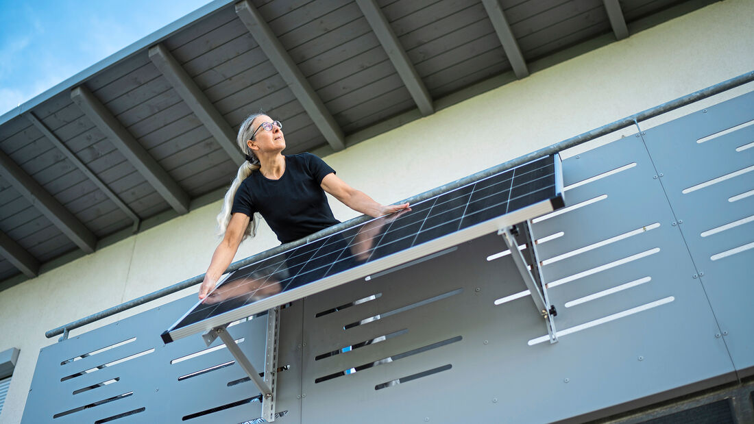 woman adjusting solar panel in direction of sunlight on her house balcony